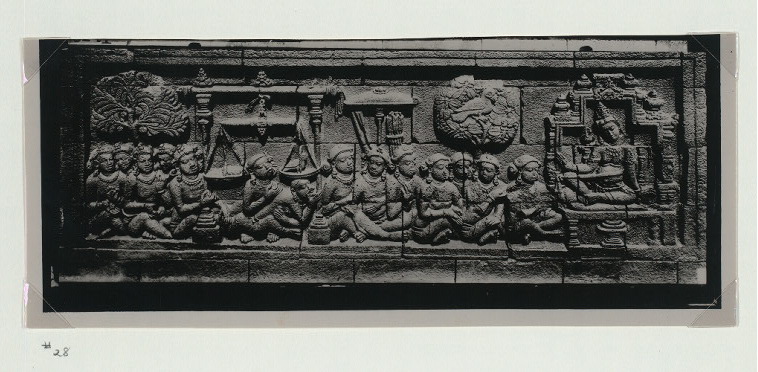 A Javanese stone relief of an enthroned king facing rows of seated courtiers beside a hanging balance