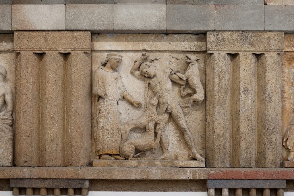 Carved stone metope showing Artemis standing beside Actaeon as hunting dogs attack him.