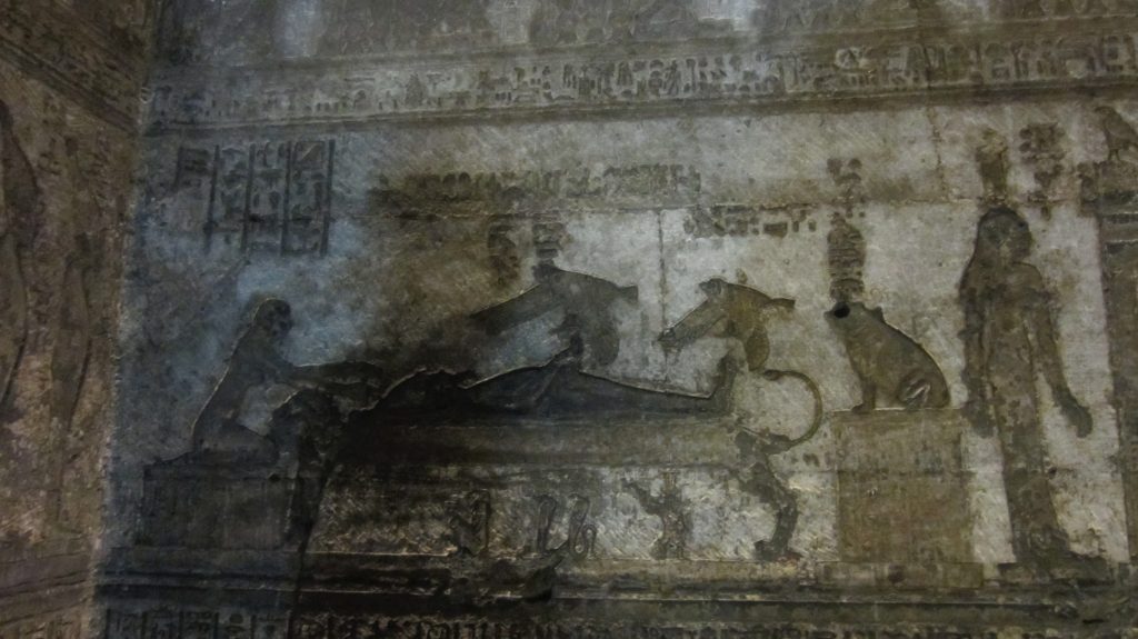 Dendera relief showing Osiris reclining on a bier with Isis in bird form above him and divine figures nearby.