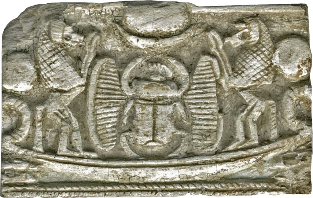 Carved stone pectoral showing a winged scarab between two standing baboons with raised hands, all above a curved solar boat.