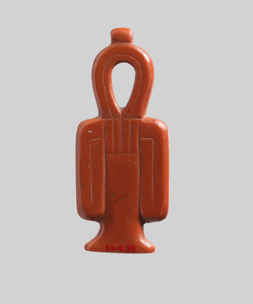 Red jasper amulet carved as a looped knot with a long central element and two folded side arms.